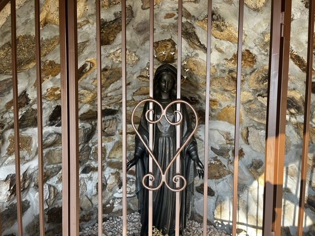 The statue of Our Lady of Grace seen through the grotto's ironwork